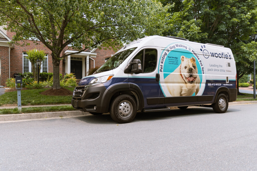 A mobile grooming van parked in front of a home